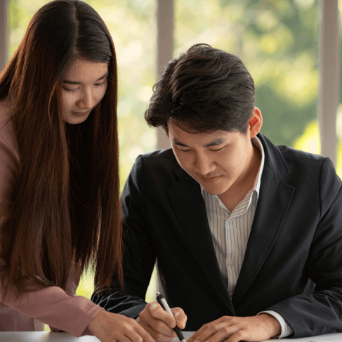 A client signs deed paperwork while a translator provides Chinese Translation Services in Pennsylvania for real estate.